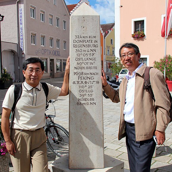Chinesische Gäste stehen am Obelisk, auf dem die Entfernung von Dietfurt nach Peking geschrieben steht.