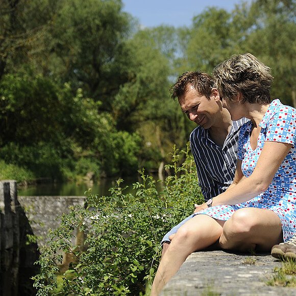 Zwei Wanderer sitzen an der alten Schleusenmauer beim Alcmonageände