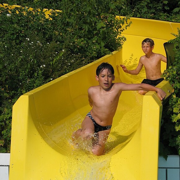 2 Jungen rutschen auf der gelben Wasserrutsche im 7-Täler-Panoramabad.