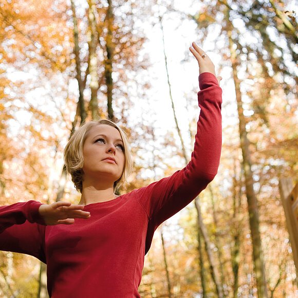 Eine Frau zeigt eine QiGong-Übung im Freien