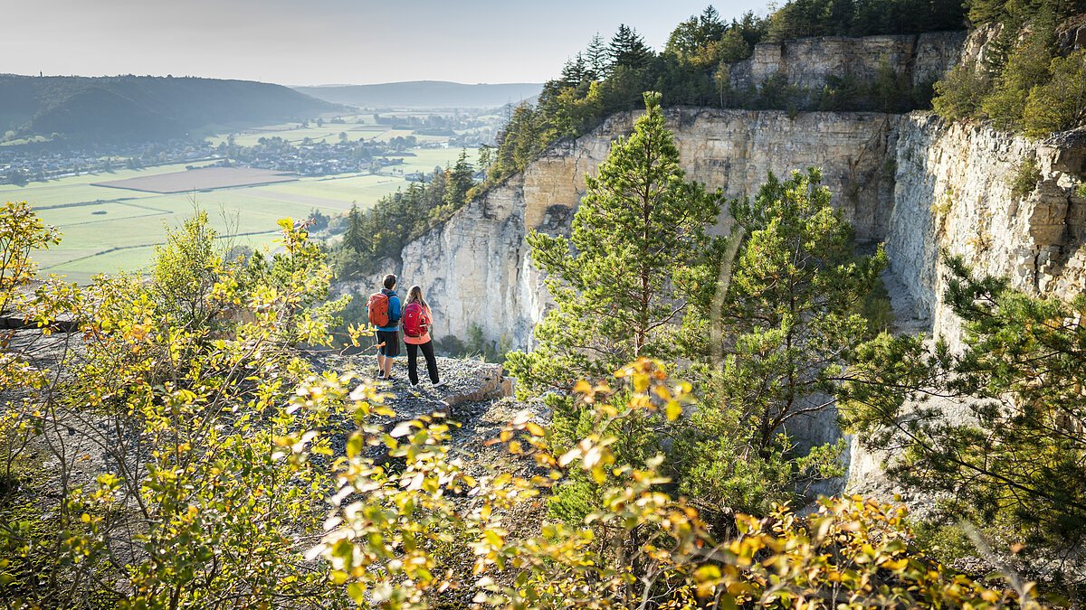 Geotop am Arzberg bei Beilngries Zwei Personen mit Rucksäcken stehen auf einem Felsvorsprung und blicken ins Tal.